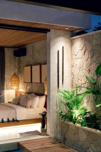 Danu Villas Bali في كيروبوكان: غرفة نوم بسرير ونبات