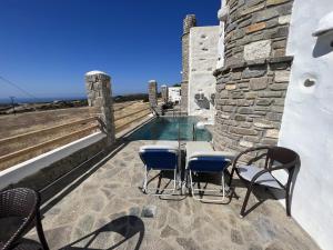 een patio met een tafel en stoelen en een zwembad bij Villa Aspro Paros 1 in Drios