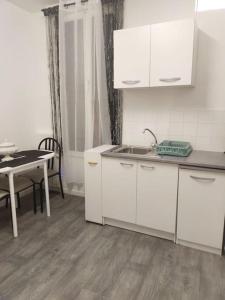 a kitchen with white cabinets and a table and a sink at Petite maison à Drancy in Drancy