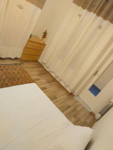 een slaapkamer met een wit bed en een gordijn bij Petite maison à Drancy in Drancy