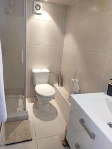 a white bathroom with a toilet and a sink at Petite maison à Drancy in Drancy