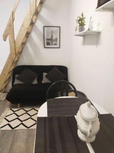 a living room with a black couch and a table at Petite maison à Drancy in Drancy