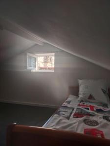 a bed in a room with a small window at Petite maison à Drancy in Drancy