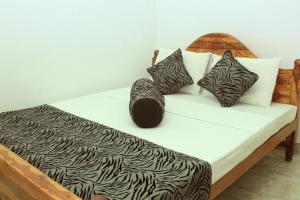 un letto con cuscini bianchi e neri sopra di Keerthi Homestay a Sigiriya
