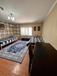 Habitación con 2 camas, mesa y alfombra. en InJoy Hostel en Shymkent