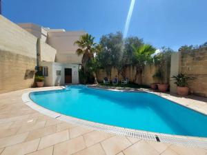 une grande piscine bleue dans une cour dans l'établissement Malta Villa, à Naxxar