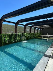 a swimming pool with blue water and green bushes at Well Hotel & Spa in Maceira