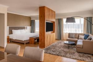 ミュンヘンにあるミュンヘン マリオット ホテルのベッドとリビングルームが備わるホテルルームです。