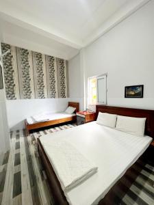 a white bedroom with a large bed and a window at Khách Sạn Chấn Phú Quý in Phú Quý