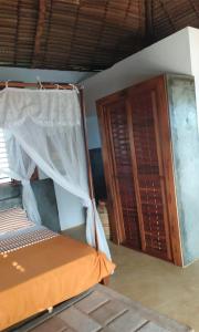 1 dormitorio con 1 cama y armario de madera en Hotel Océan Beach Sakatia, en Nosy Be