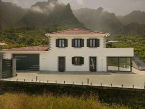 a white house with mountains in the background at Casa Avô da Pedra, By OP in São Vicente