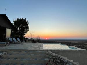 a sunset from a patio with stairs and chairs at Aloegrove Safari Lodge in Otjiwarongo