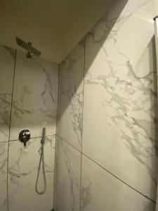 La salle de bains est pourvue d'une douche et de murs en marbre blanc. dans l'établissement Maison Dante, à Naples