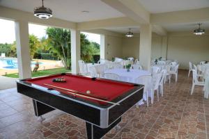 una mesa de billar en una habitación con mesas y sillas blancas en Villa Rocio - Country Villa with pool en San Juan de la Maguana