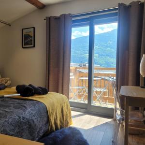 1 dormitorio con cama y vistas a un balcón en gîteduruisseau73, maison entière 80m2 au calme, 2 chambres 2 salles de bain avec terrasse et garage, en Bourg-Saint-Maurice