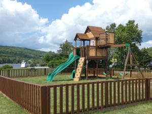 a playground with a tree house and a slide at The Cove Motel & Restaurant in Aulds Cove