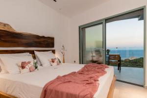 a bedroom with a bed and a large window at Sky Birds Villa - Holistic Escape in Skinária