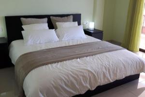 1 dormitorio con 1 cama grande con sábanas y almohadas blancas en Apartamento Neptuno, en Candelaria
