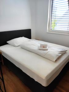 a bed with white sheets and a hat on it at Luxuriöses Penthouse mit Blick auf die UNO-City und dem Kaiserwasser. 3Schlafzimmer, 2 Bäder, privat Lift ins Apartment in Vienna