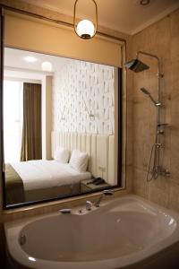a bathroom with a tub and a bed in a mirror at Port Plaza YVN in Pʼarakʼar