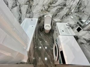a marble bathroom with a sink and a toilet at Жк «Комфорт сити» in Almaty
