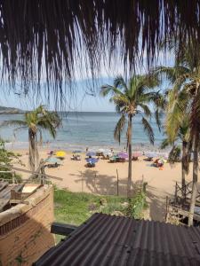 a beach with palm trees and people on the beach at Posada Ecohabitas in Mazunte