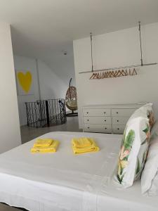 um quarto branco com uma cama com toalhas amarelas em Apartamento duplex Mediterránean view em Gandia