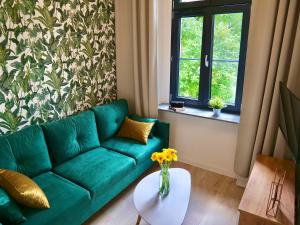 salon z zieloną kanapą i stołem w obiekcie Loft Apartments Gliwice w mieście Gliwice
