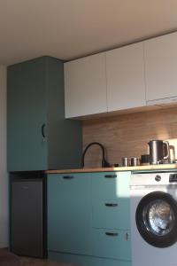 a kitchen with blue cabinets and a washing machine at Cottage Milo Kazbegi in Kazbegi