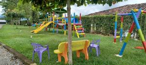 un parque infantil con coloridos equipos de juego en el césped en Finca Hotel El SAMAN de alto bonito, en Montenegro