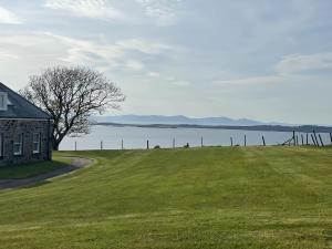 uma casa num campo relvado ao lado de uma massa de água em Harebell Cottage em Killean