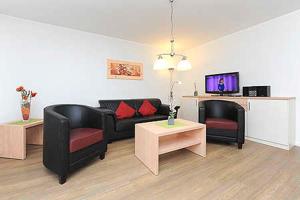 a living room with black furniture and a flat screen tv at Ferienwohnungen Am Sieltor in Bensersiel