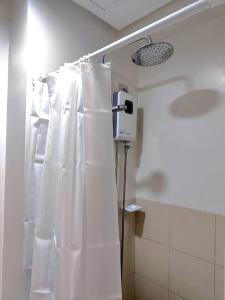 a bathroom with a shower with a white shower curtain at Condo in Quezon City, Trees Residences Tower 16 in Manila