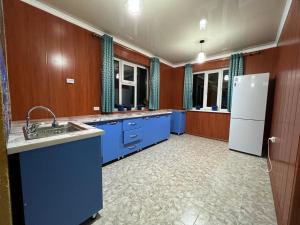 eine Küche mit blauen Schränken und einem weißen Kühlschrank in der Unterkunft Guest House Dinara in Kaji-Say