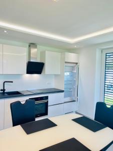 a kitchen with white cabinets and blue chairs at City Apartments in Herzogenaurach