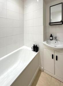 a white bathroom with a tub and a sink at Modernist Studio in Fitzrovia in London
