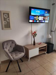 ein Wohnzimmer mit einem Stuhl und einem TV an der Wand in der Unterkunft Apartamento HAKUNA MATATA con gran terraza, planta baja in Playa de San Juan