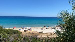 a group of people on a beach with the ocean at House pinus village in Forte Village +5 photos