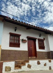 une maison blanche avec deux fenêtres et une porte dans l'établissement Casa Victoria, à Zapatoca
