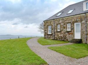 a stone house with a gravel path leading to it at Honeysuckle Cottage in Killean