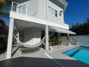 a house with a hammock and a swimming pool at Casa ideal no Guaruja in Guarujá