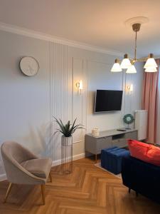 Sala de estar con sofá, silla y TV en Bella Casa Luxury Apartament en Radom