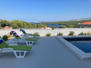 a group of chairs sitting next to a swimming pool at Villa Bay View in Stari Grad