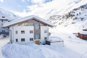 a building covered in snow with a mountain in the background at Chalet Cecilia by MYALPS in Obergurgl