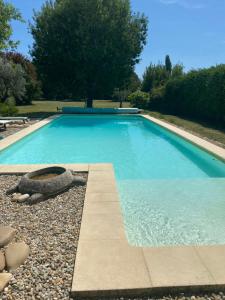 a blue swimming pool with a stone curb at Gîte cosy in Orange