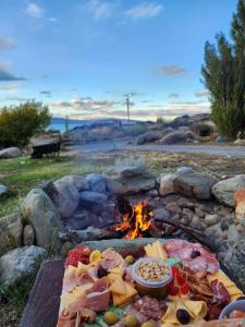 a fire pit with a bunch of meats and cheese at Brillos Patagónicos in El Calafate