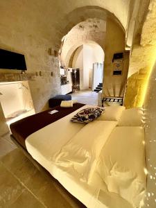 een slaapkamer met een groot wit bed in een stenen kamer bij CASA VACANZE BB 164-166 in Matera