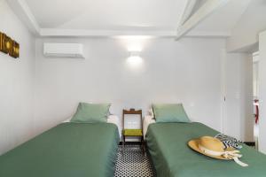 Habitación con 2 camas verdes con sombreros. en Wonderland House Leiria en Leiria