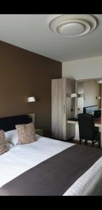 a bedroom with a large white bed and a desk at Belrom Hotel in Sint-Truiden