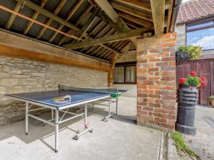 a ping pong table in a patio with a brick wall at Magpie cottage in Pickering